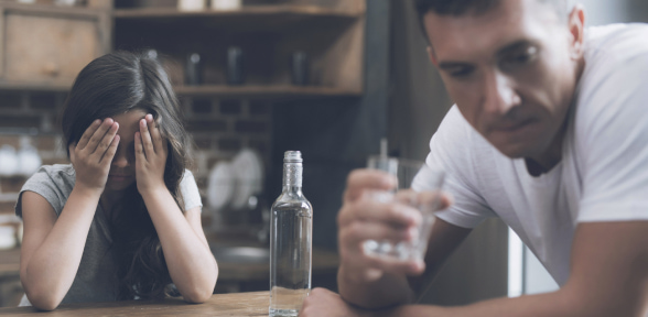 Dievčatko plače a zakrýva si tvár, alkoholický otec sa hanebne otáča.